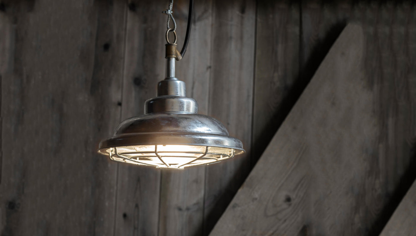 Galvanised pendant light for outdoor seen in front of a wooden gate