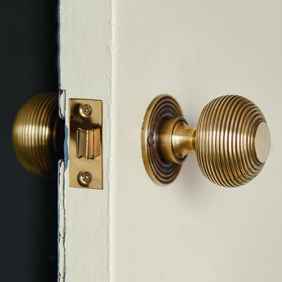 Brass beehive door knobs shown on a mortise latch on a door