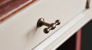 Brass drawer pull handle in the form of a tap on a cream drawer