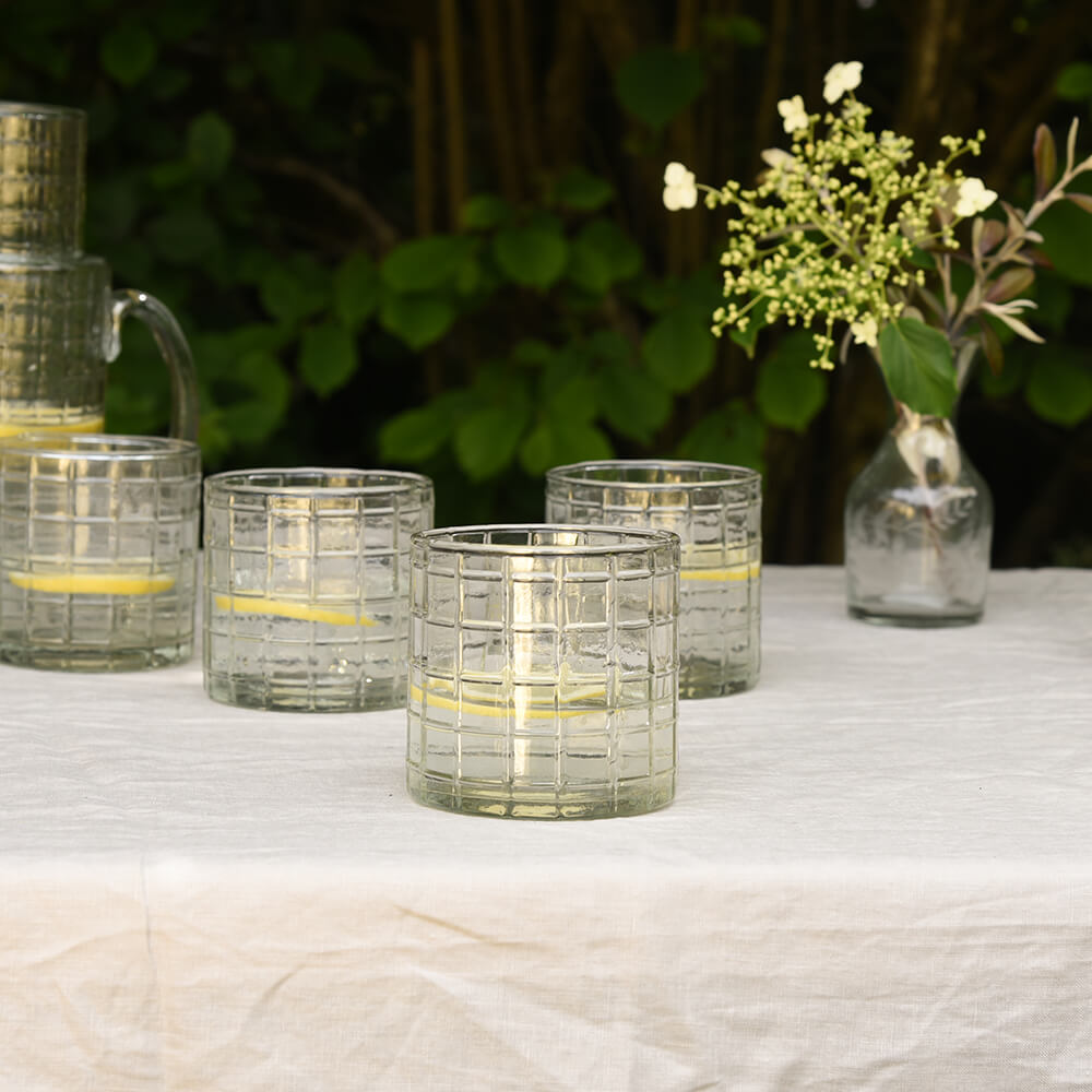 Chequerd glass tumblers on table with flowers in vase