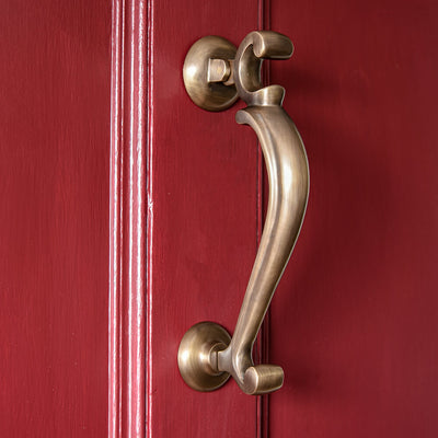 brass doctor door knocker with elegant curves on a red door