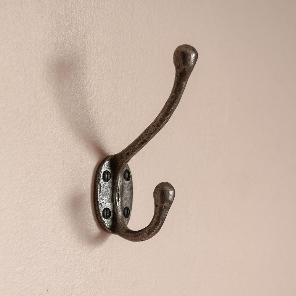cast iron double coat hook mounted on pink wall