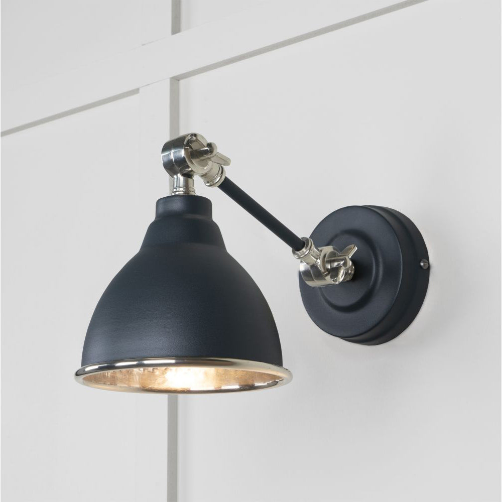Hammered nickel Brindley wall light in black against a white panelled wall