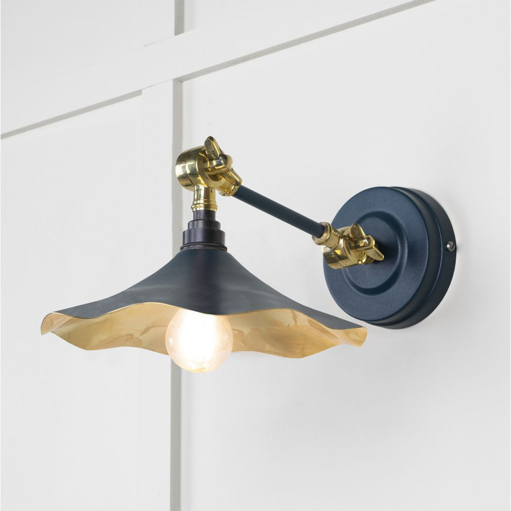 Smooth brass flora wall light in dusk against a white panelled wall