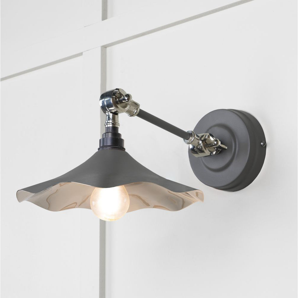 Smooth polished nickel flora wall light in bluff against a white panelled wall