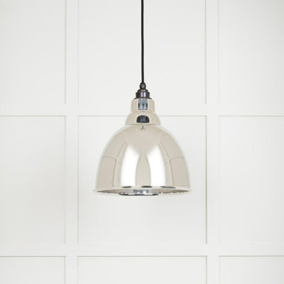 Smooth polished nickel Brindley pendant light hanging from a black fabric cord against a white panelled wall