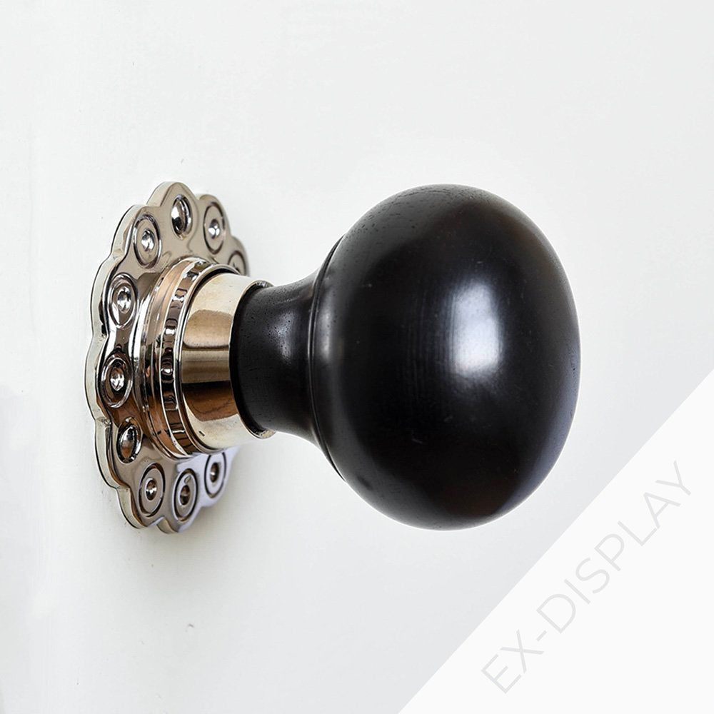 Solid ebony bun door knob with polished nickel petal backplate on a light grey background iwth a watermark and ex display text in the corner