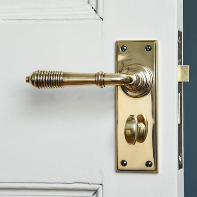A Reeded Lever Handle with bathroom lock in an aged brass finish