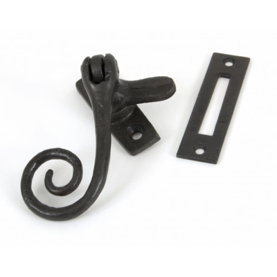 A monkeytail window fastener with a spiral handle design and lock keep in black beeswax positioned for a righthand window