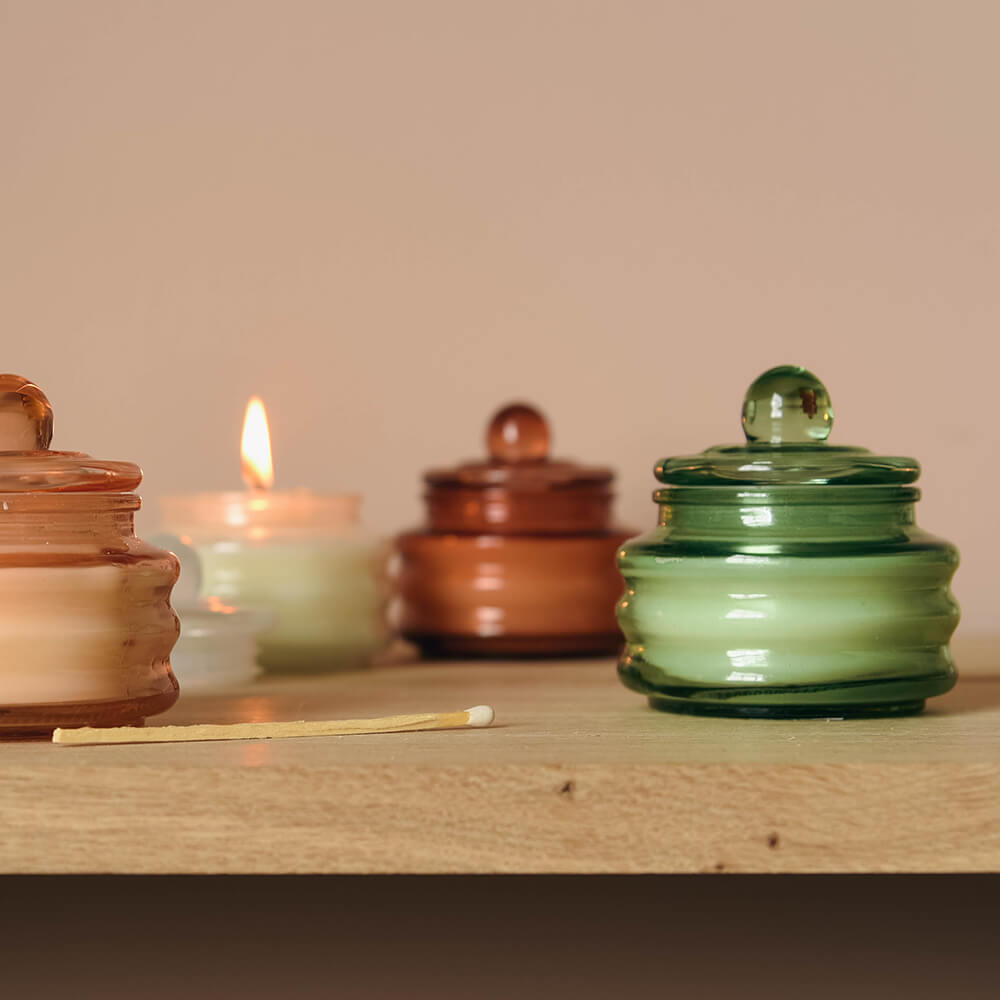 selection of candles in glass vessels with lit candle
