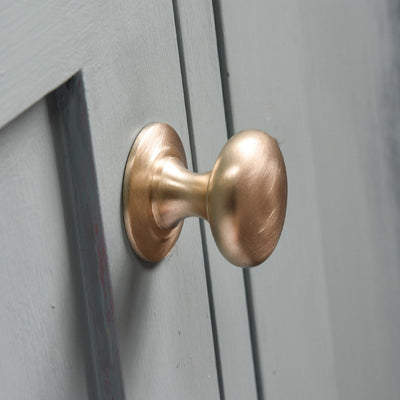 Solid Brass Cabinet Knob in brushed finish on cupboard door.