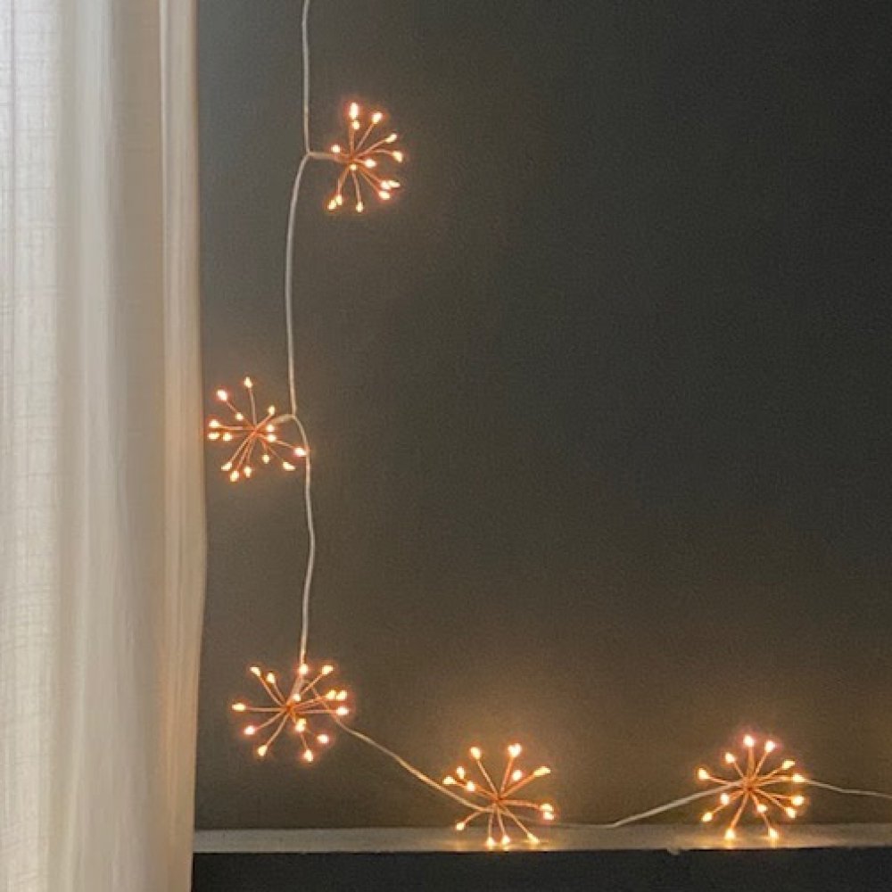 Chain of fairy lights with copper starbursts by window