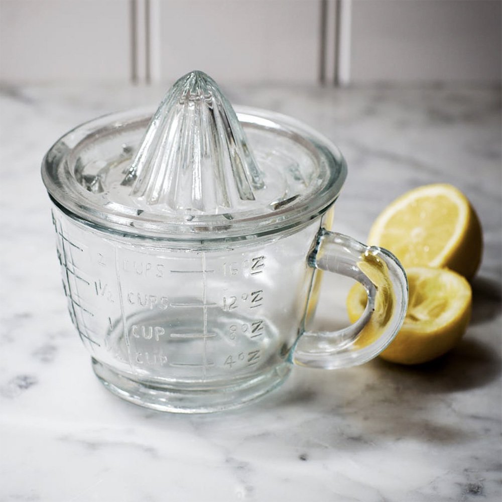 Glass measuring jug with handle topped with glass citrus squeezer as lid