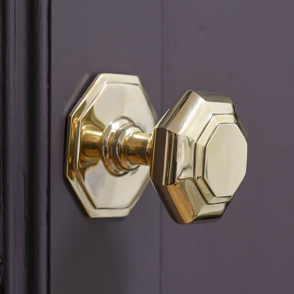 Small octagonal brass door pull on purple background