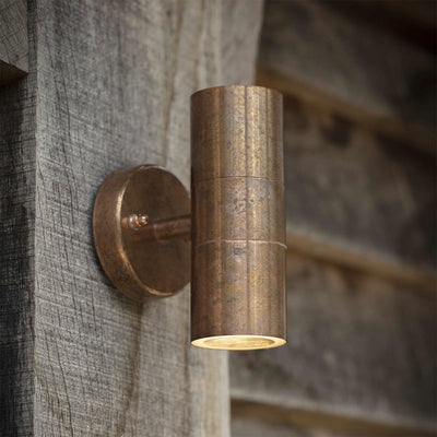 Raw copper wall mounted outdoor up and down light in simple cylindrical design. Image showing natural patina from outdoor exposure