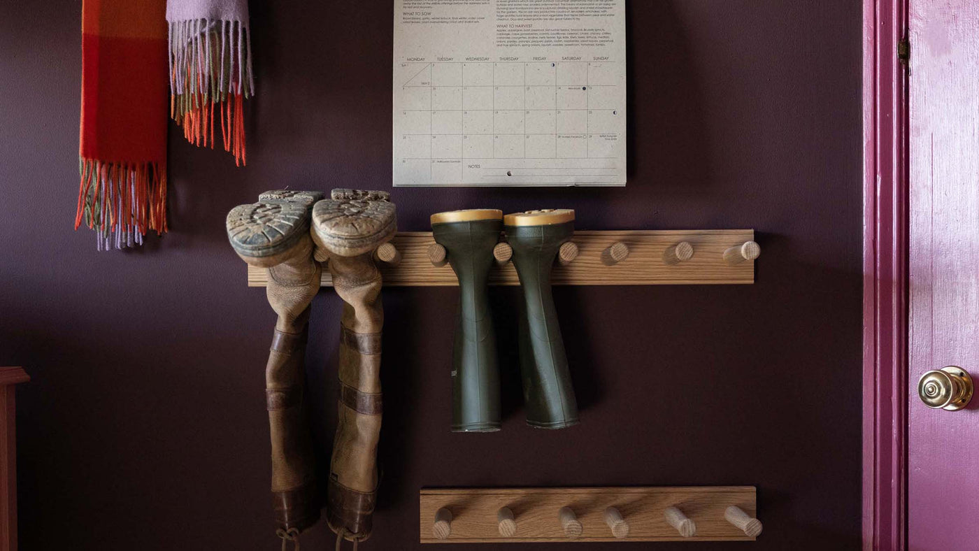 Oak welly boot racks in hallway on deep mauve wall