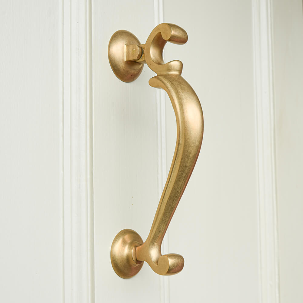 Brass doctors door knocker in an aged finish on white door