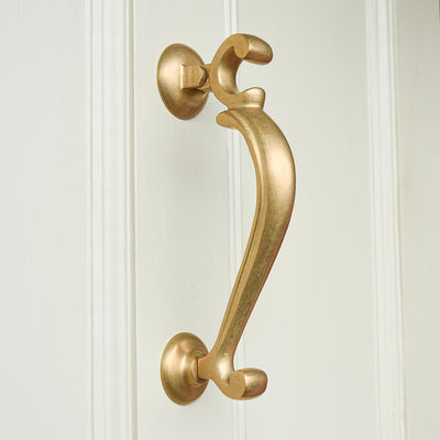 Brass doctors door knocker in an aged finish on white door