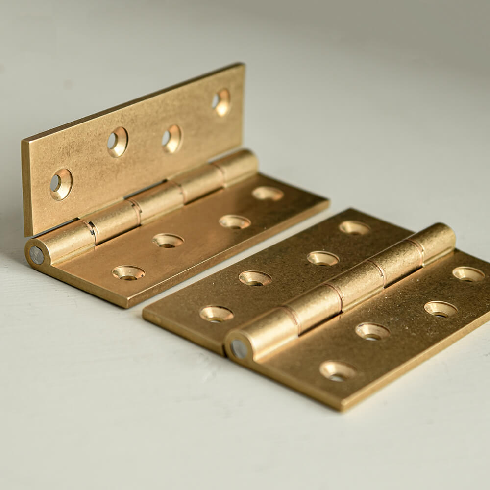 A pair of aged brass butt hinges on a board