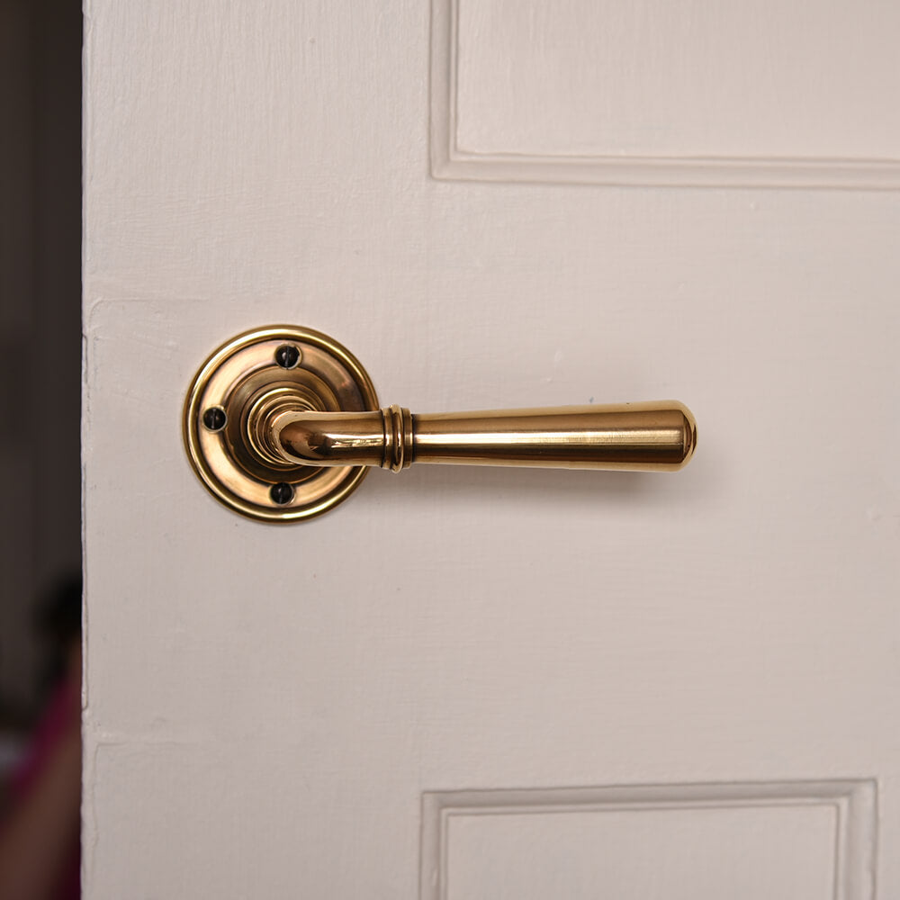 Polished antique brass lever handle on off white door
