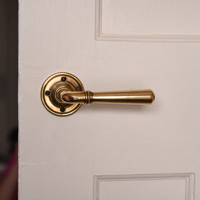 Polished antique brass lever handle on off white door