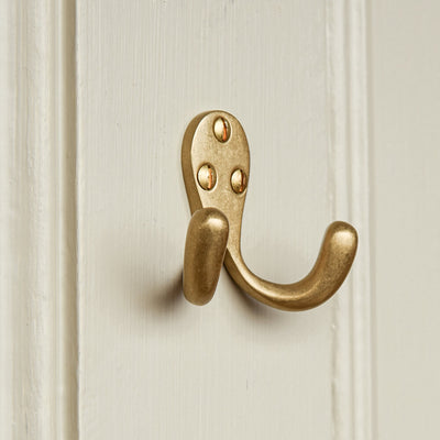 Brass wall hook on a textured beige wall