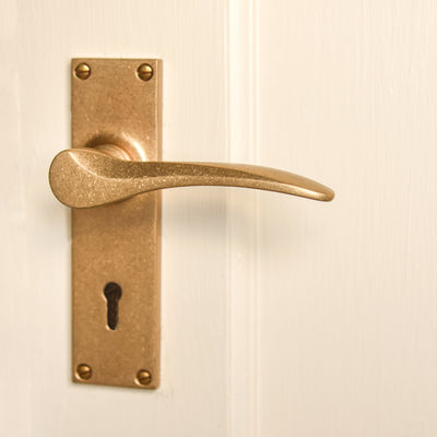 Aged Brass Penwerris Lever Lock Handles on a cream painted door