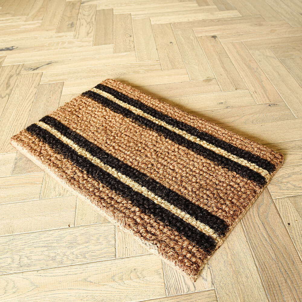 Striped doormat with brown and black stripes on a wooden floor