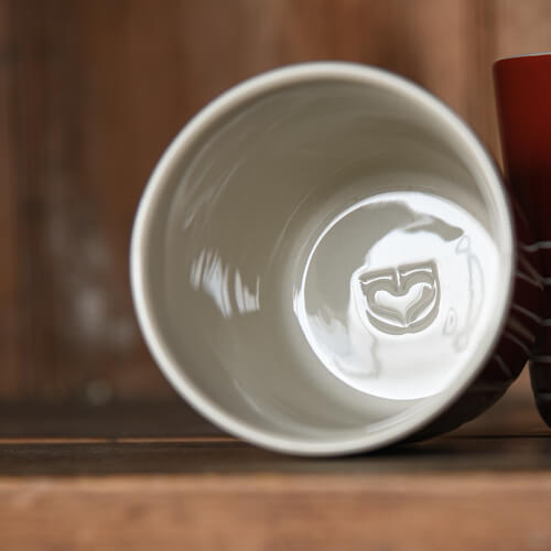 White ceramic cup with a logo on a wooden surface