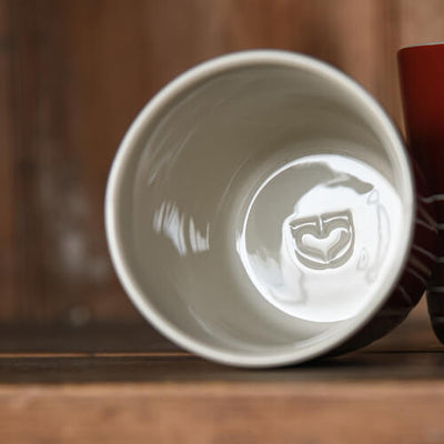 White ceramic cup with a logo on a wooden surface