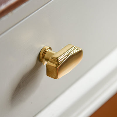 Angular brass cabinet knob on a white cabinet