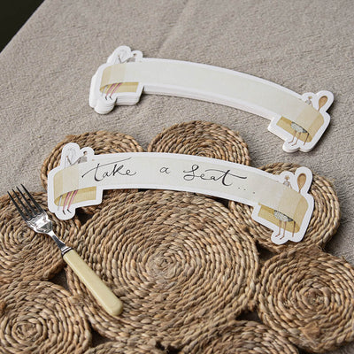Decorative place card holder with 'Take a Seat' text on a textured surface with a fork.