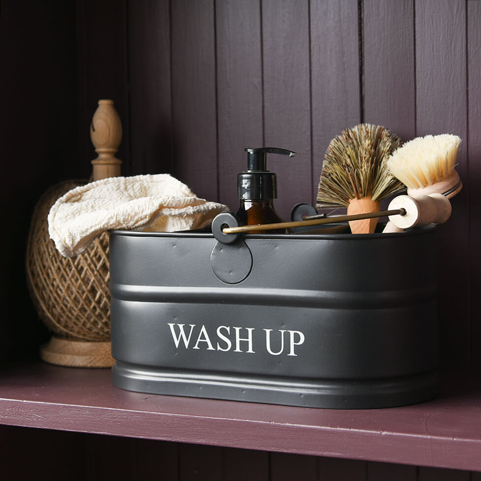 Black metal wash basin with 'WASH UP' text, containing shaving tools on a wooden shelf.