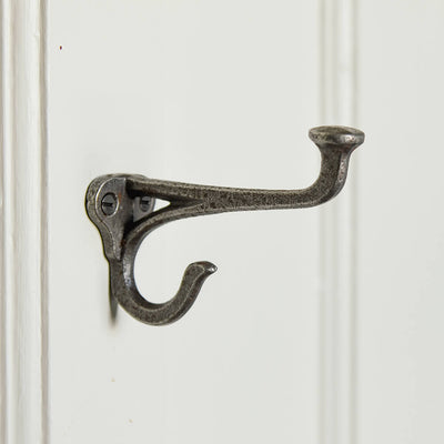 double cast iron hook with an elongated top hook mounted on an off white door
