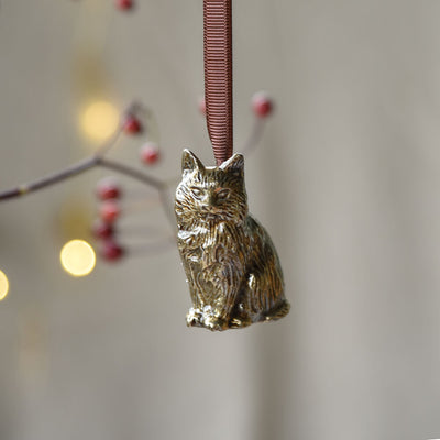 Bronze cat ornament on a blurred background with lights and berries
