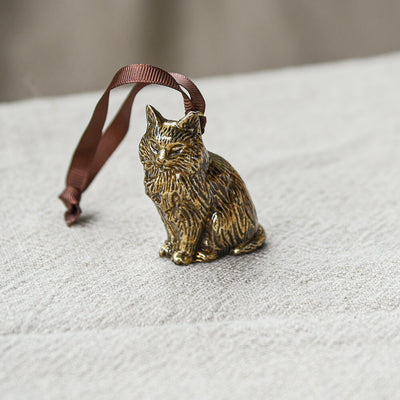 Bronze cat ornament with a brown ribbon on a textured surface