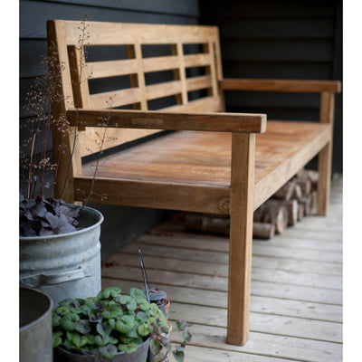 Teak chastleton bench on wooden porch with plants in the foreground
