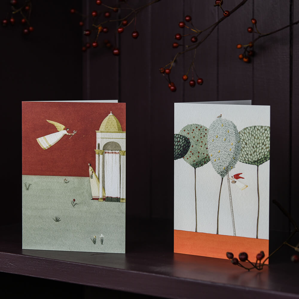 Two greeting cards with artistic designs on a dark surface.