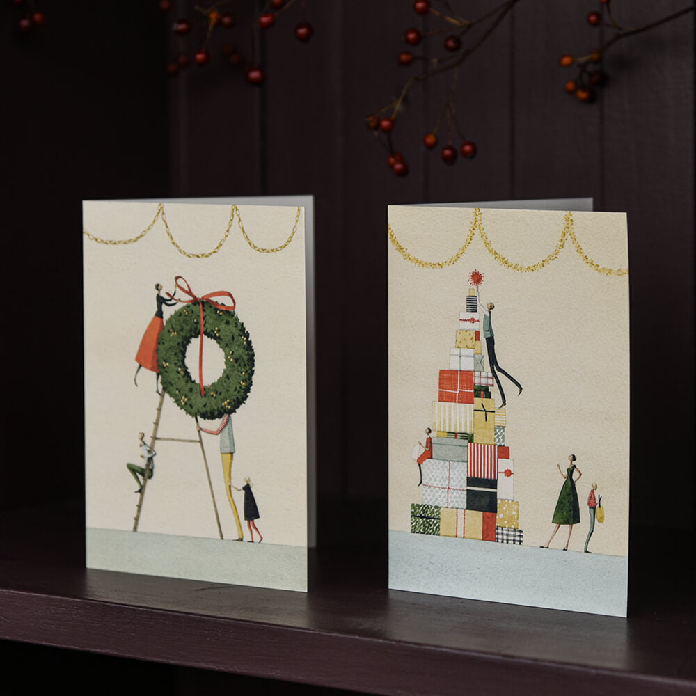 Two greeting cards with festive designs on a dark surface.
