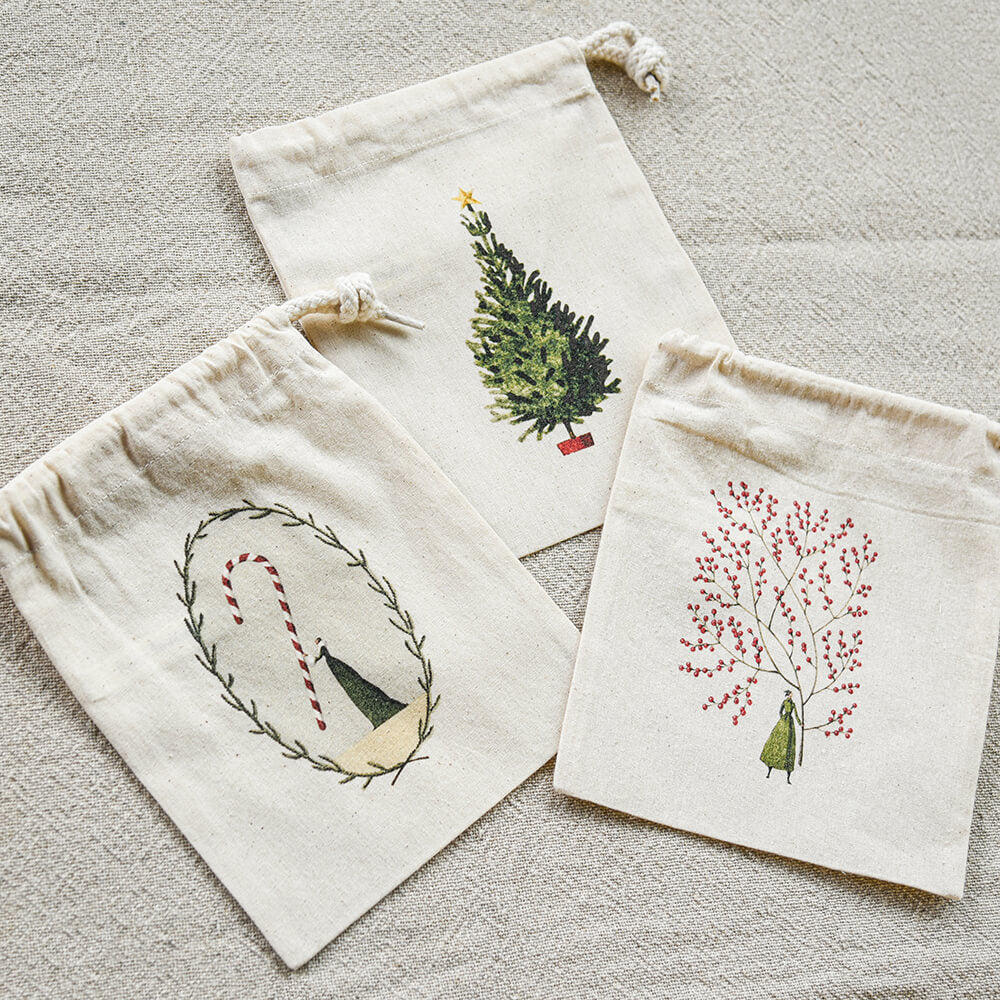 Three decorative drawstring bags with printed designs on a textured surface