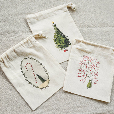 Three decorative drawstring bags with printed designs on a textured surface