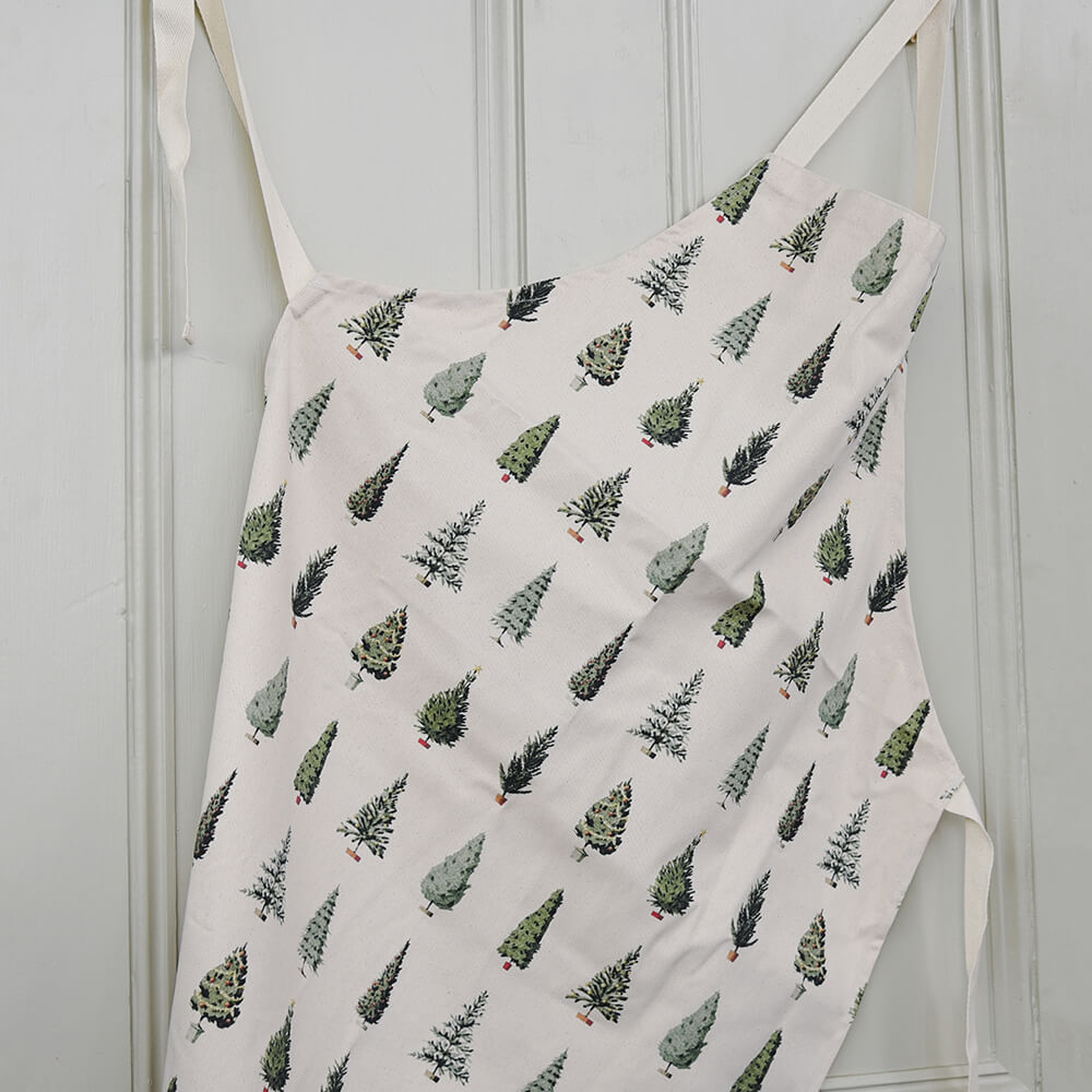 Apron with Christmas tree pattern hanging on a white wall