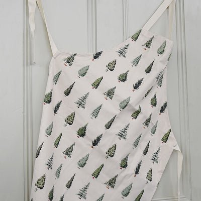 Apron with Christmas tree pattern hanging on a white wall