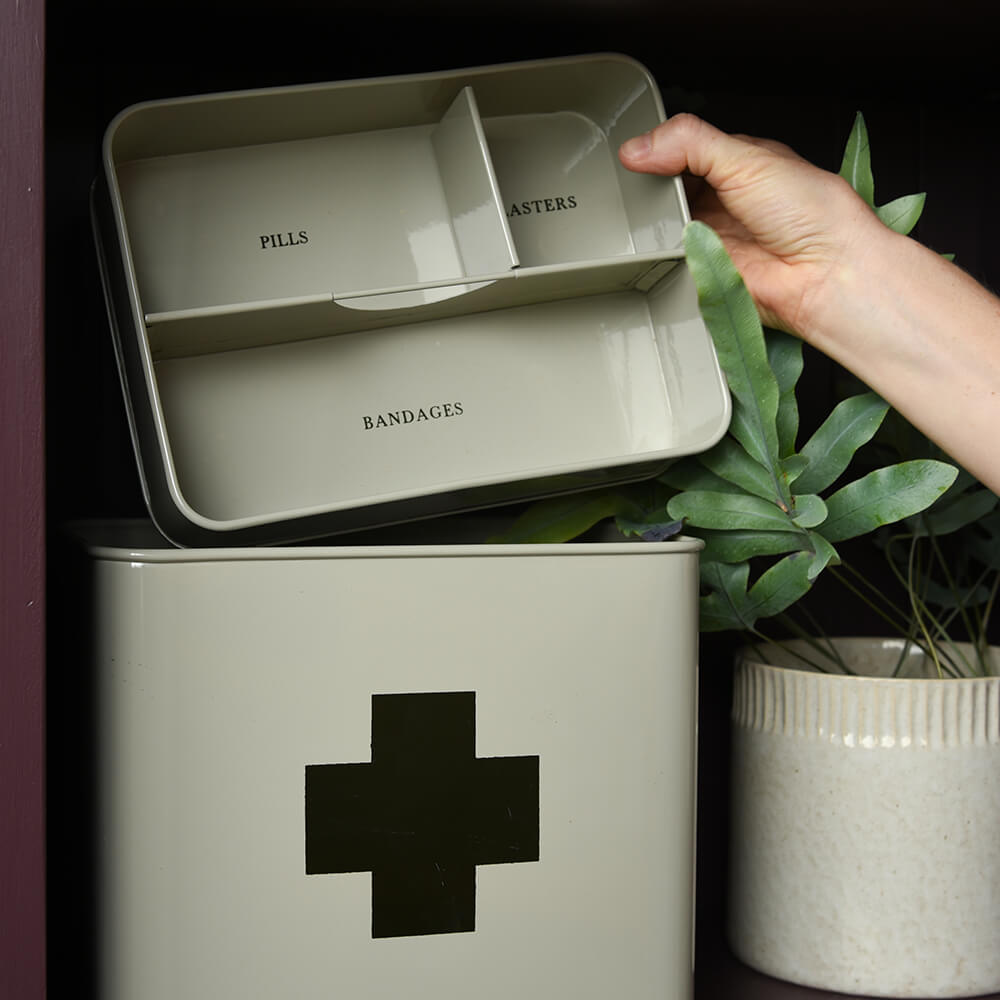 Medicine cabinet with labeled compartments and a hand reaching for a container.