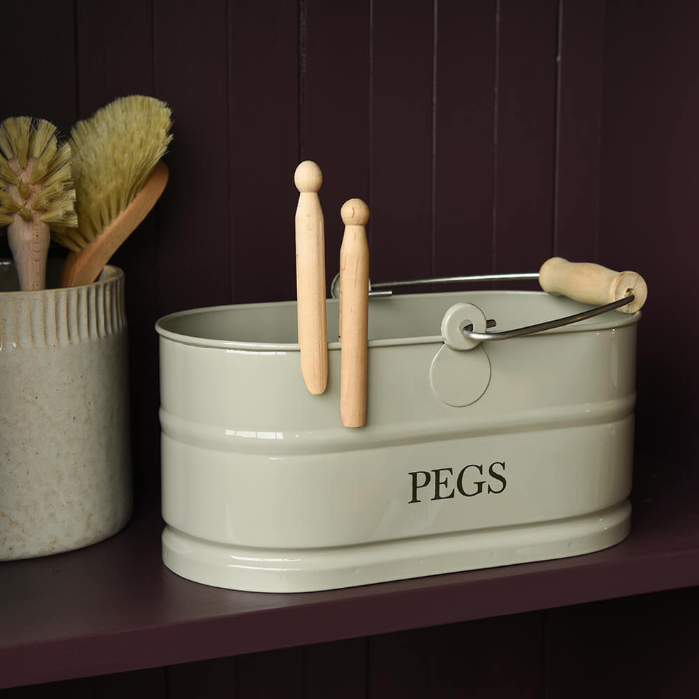 Clay metal basket labeled 'PEGS' with wooden pegs on a dark background