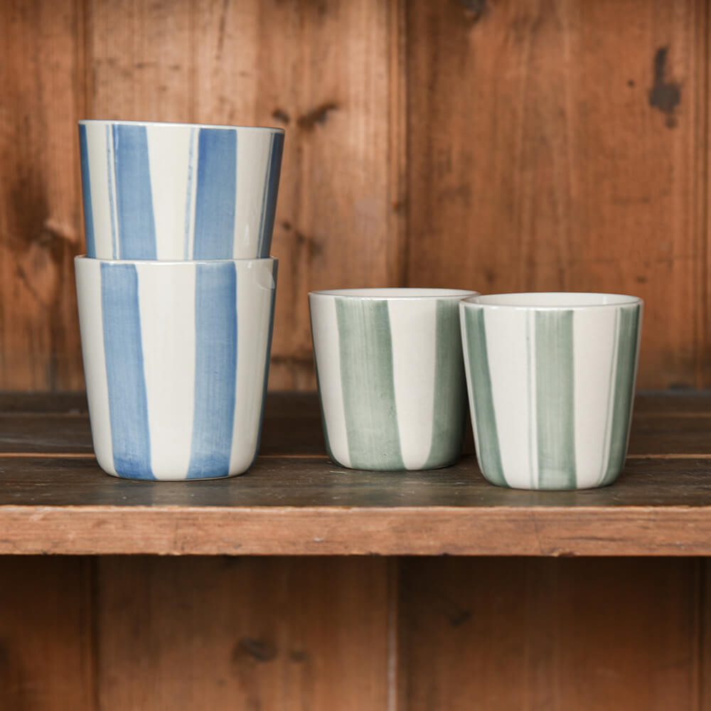 Four striped ceramic beakers on a shelf