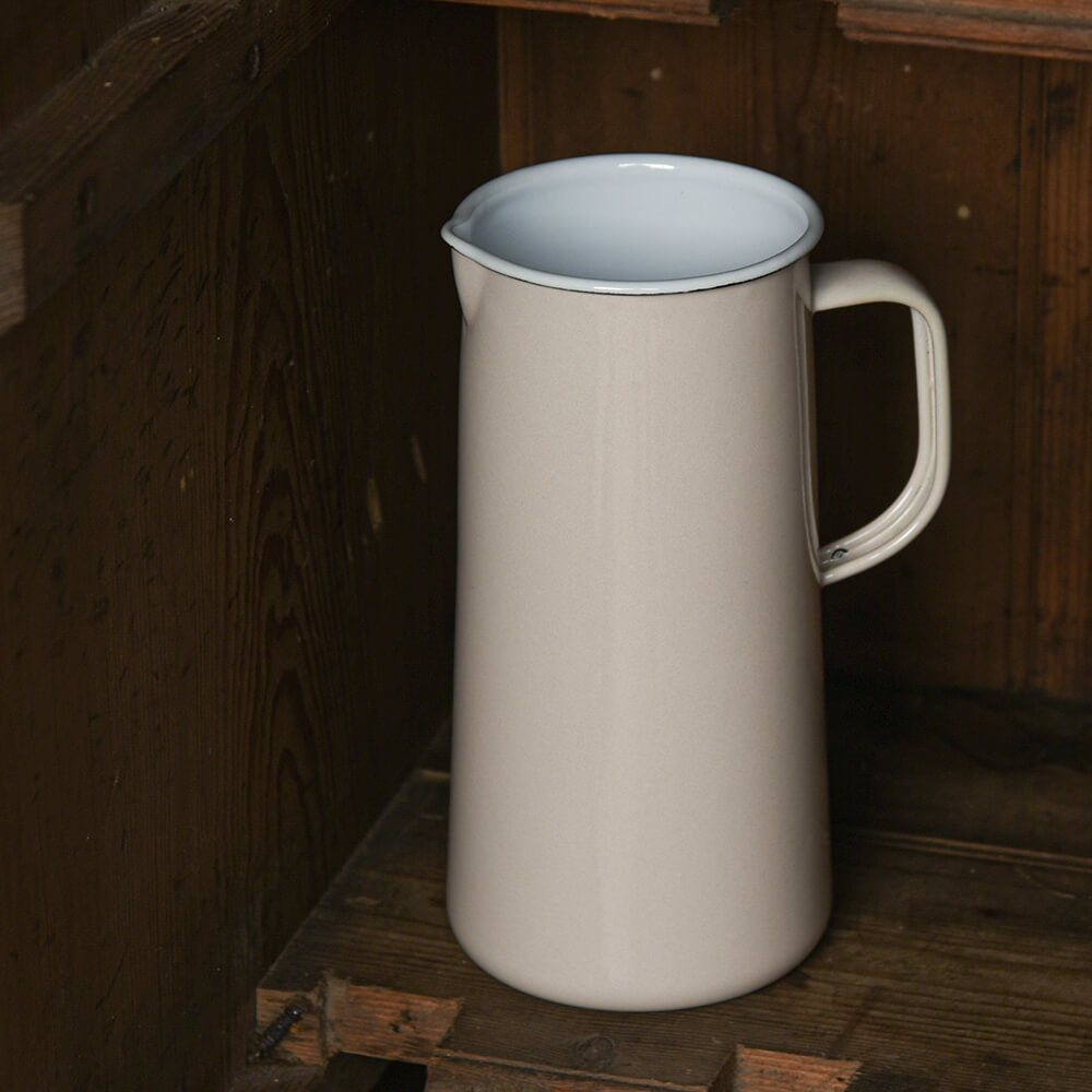 Beige ceramic pitcher with a light blue interior on a wooden surface