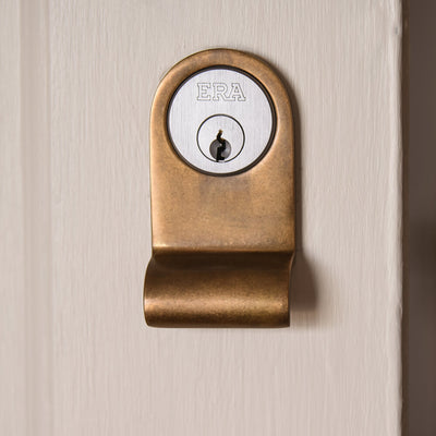 Aged brass cylinder latch pull on a door showing latch