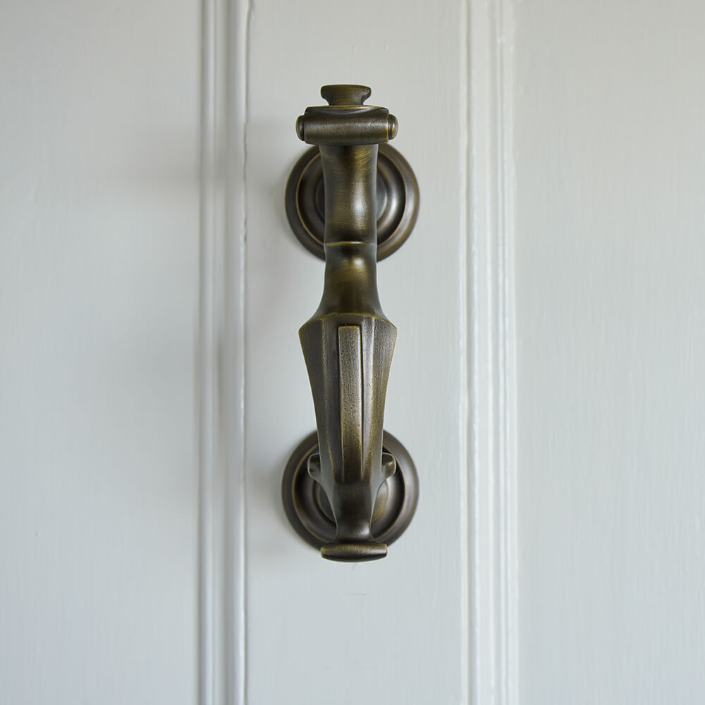 Darkened brass door knocker in an elegant ornate style seen from the front