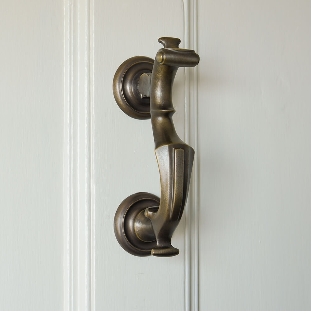 Darkened brass door knocker in an elegant ornate style